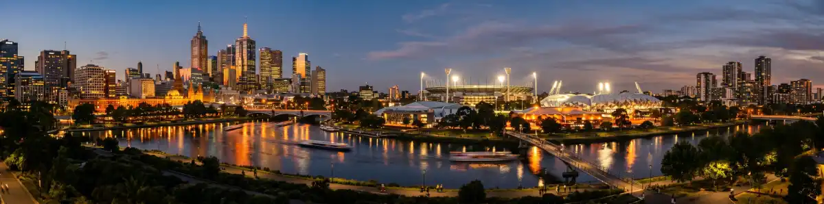 Melbourne CBD and Richmond skyline at dusk with hotel buildings illuminated and the Yarra River reflecting city lights