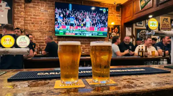 Two pints of craft beer at an Australian pub near Sydney Olympic Park with rugby league on screen
