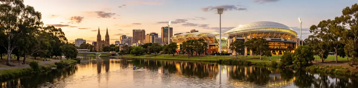 Adelaide Oval at golden hour viewed from across the River Torrens with the city skyline and St Peter's Cathedral behind