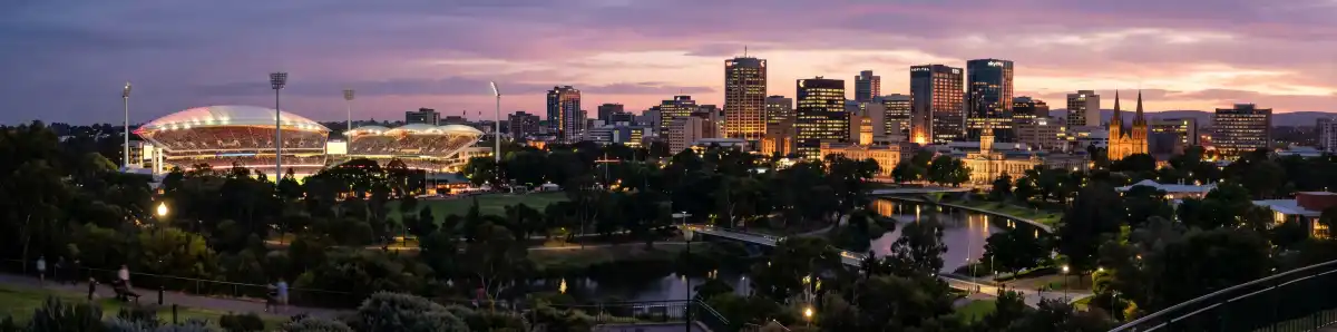 Adelaide city skyline at dusk viewed from North Adelaide with Adelaide Oval roof lit up and hotel towers illuminated
