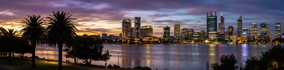 Perth city skyline at dusk viewed from Burswood across the Swan River with Crown Perth towers and hotel buildings illuminated