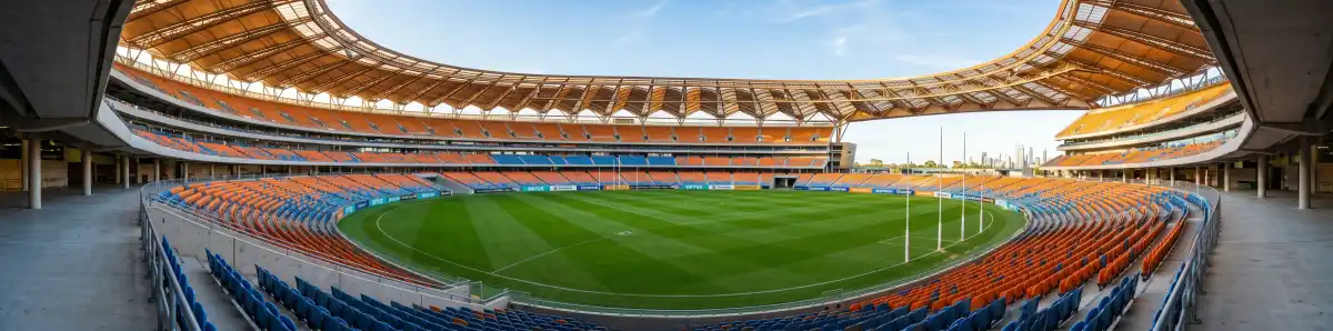 Inside Optus Stadium Perth looking across the empty playing field with bronze roof structure and rows of orange and blue seats
